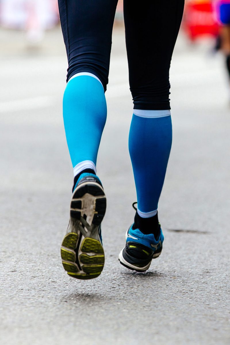 back feet woman runner in blue compression socks running street